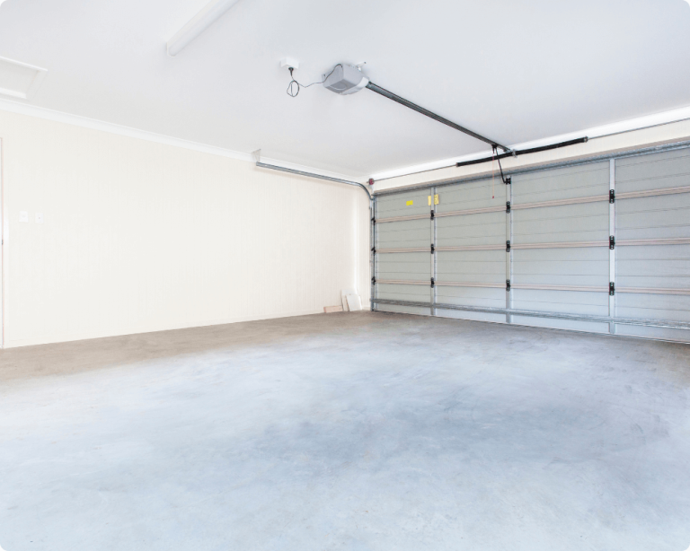 Bright, empty garage with a concrete floor and automatic garage door, featuring light-colored walls and minimal fixtures.